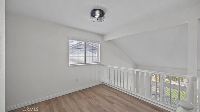 additional living space featuring baseboards, lofted ceiling with beams, and wood finished floors