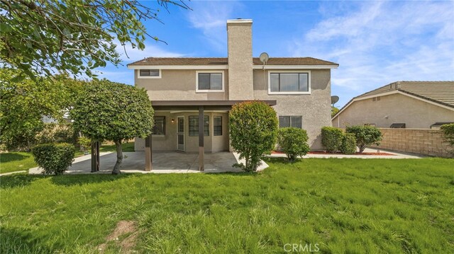 rear view of property with a lawn, a chimney, a patio area, and stucco siding