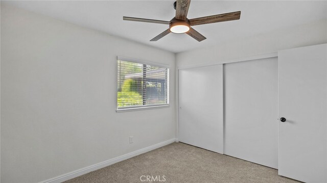 unfurnished bedroom with ceiling fan, light carpet, baseboards, and a closet