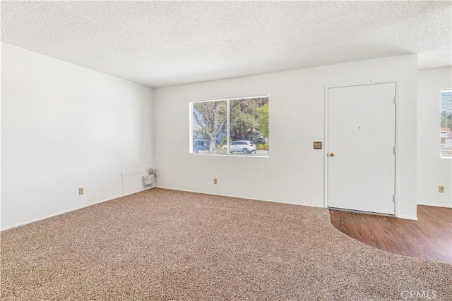 carpeted empty room with a textured ceiling