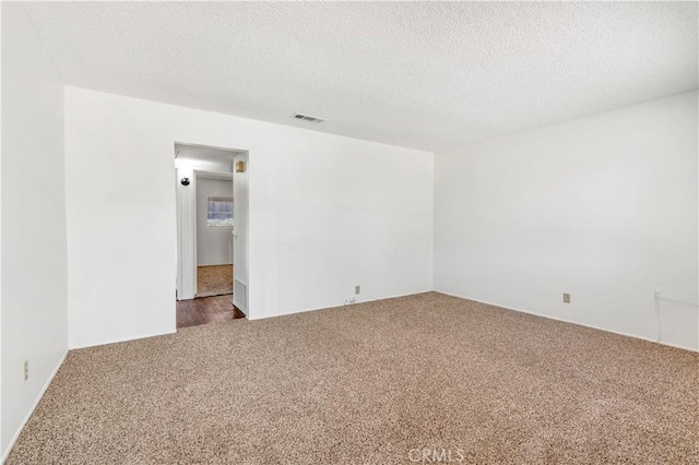 carpeted empty room with a textured ceiling and visible vents