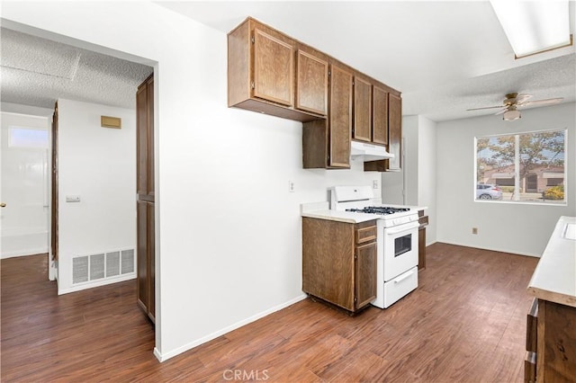 kitchen featuring light countertops, visible vents, white range with gas stovetop, and under cabinet range hood