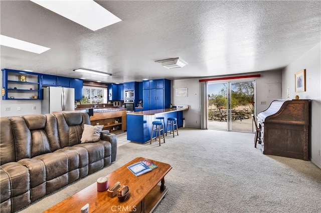 living room featuring a skylight, a textured ceiling, and light colored carpet