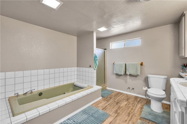 bathroom with toilet, wood finished floors, a textured ceiling, a stall shower, and baseboards