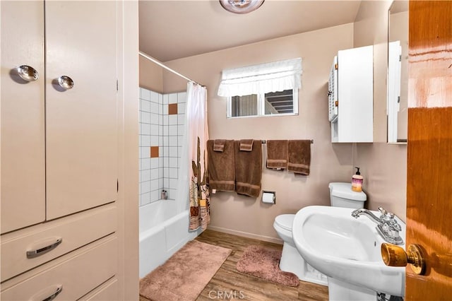 full bathroom with wood finished floors, a sink, shower / bath combination with curtain, baseboards, and toilet