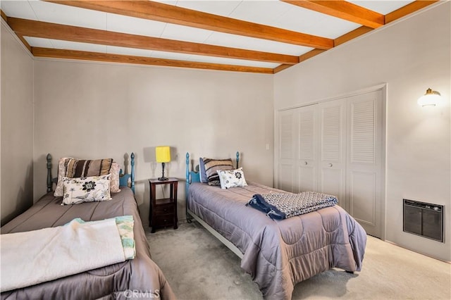 bedroom featuring beamed ceiling, carpet, and a closet