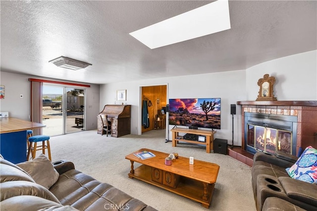carpeted living area featuring a skylight, a tile fireplace, and a textured ceiling