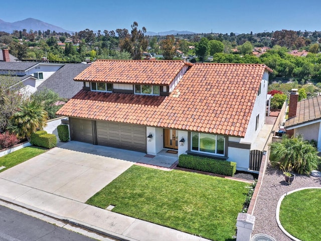 mediterranean / spanish home with a front lawn, a mountain view, driveway, a tiled roof, and stucco siding