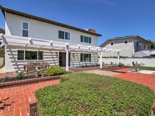 back of property with stucco siding, a pergola, and a patio