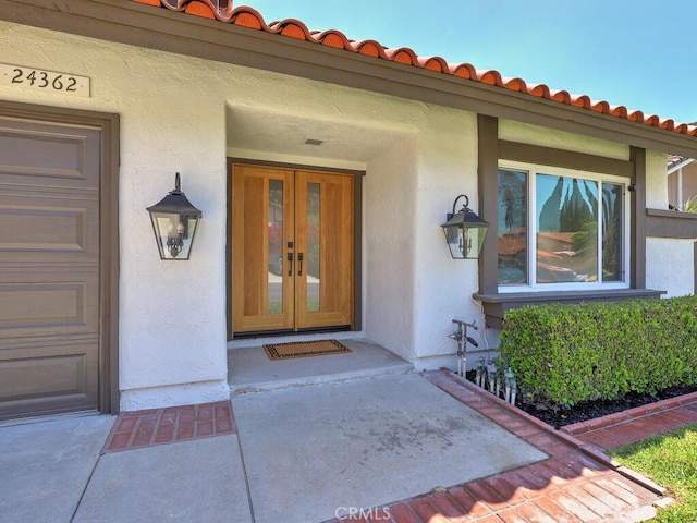 property entrance featuring french doors, a tile roof, and stucco siding