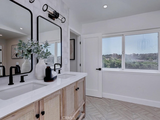 bathroom featuring a wealth of natural light, a sink, and baseboards