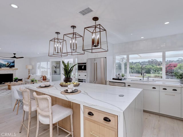 kitchen featuring a center island, a sink, light wood-style floors, stainless steel appliances, and visible vents