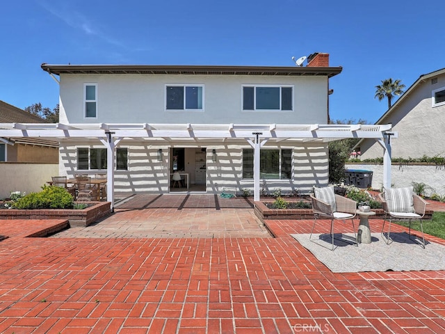 back of property featuring stucco siding, a chimney, a pergola, and a patio area
