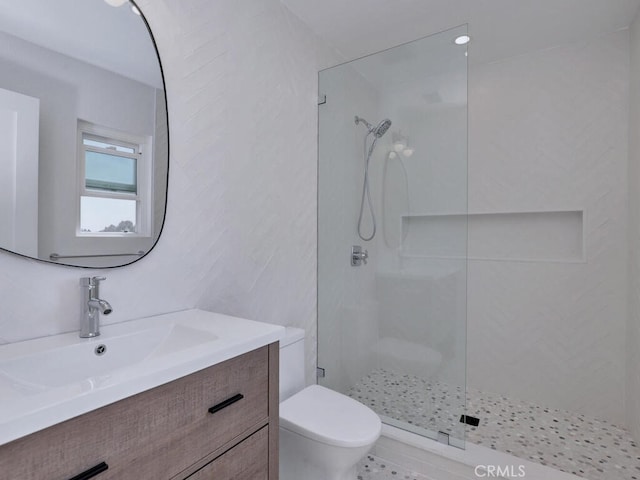 bathroom featuring vanity, a walk in shower, and toilet