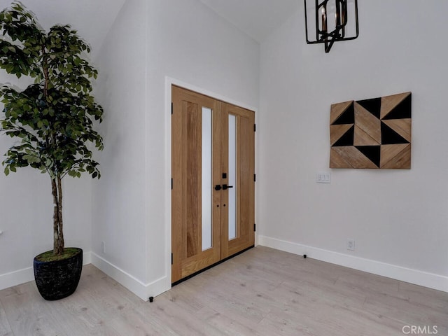 foyer entrance featuring high vaulted ceiling, baseboards, french doors, and wood finished floors