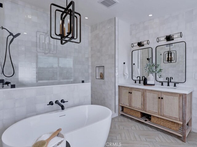 bathroom featuring a sink, double vanity, a freestanding bath, visible vents, and tiled shower
