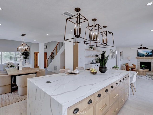 kitchen with light stone counters, recessed lighting, open floor plan, visible vents, and a kitchen island