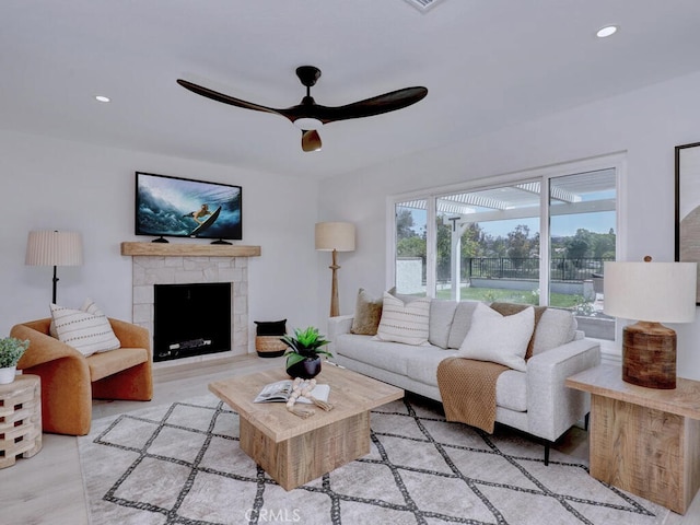 living area with ceiling fan, a stone fireplace, wood finished floors, and recessed lighting