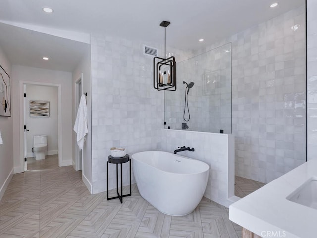 bathroom featuring a freestanding bath, tile walls, walk in shower, and recessed lighting