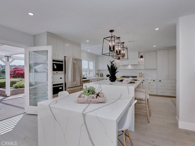 kitchen with a spacious island, a chandelier, white cabinets, appliances with stainless steel finishes, and recessed lighting