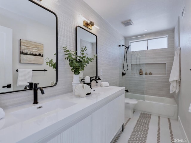 bathroom featuring toilet, a sink, shower / bathing tub combination, and visible vents
