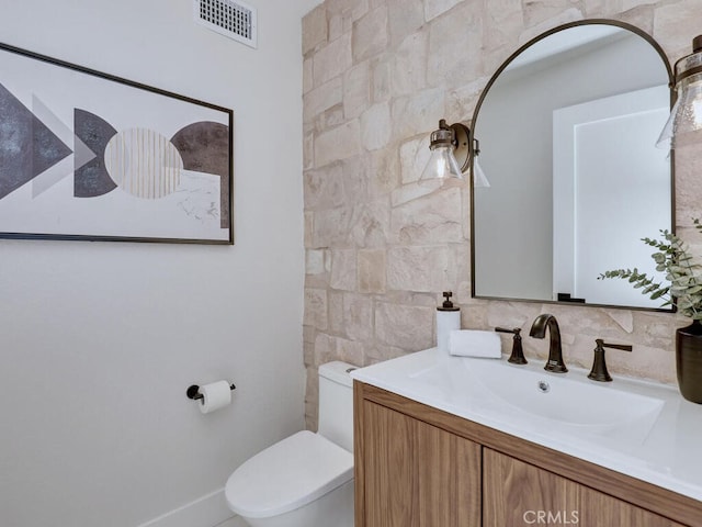half bathroom with tile walls, visible vents, toilet, and vanity