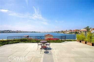 view of patio / terrace featuring a water view and fence