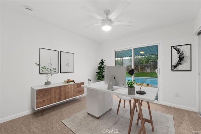 office featuring baseboards, light carpet, and ceiling fan