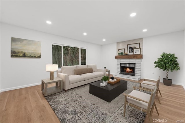 living room with a brick fireplace, recessed lighting, light wood-style flooring, and baseboards