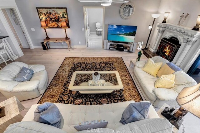 25641 Rapid Falls Rd, Laguna Hills, CA 92653 - living room featuring a lit fireplace, a ceiling fan, wood finished floors, and baseboards