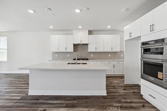 16669 Dara Ave, Chino, CA 91708 - kitchen with dark wood-style floors, light countertops, tasteful backsplash, white cabinets, and an island with sink