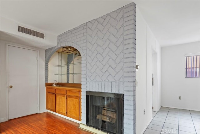 21900 Roscoe Blvd Unit 5, Canoga Park, CA 91304 - unfurnished living room featuring baseboards, a brick fireplace, a sink, and visible vents