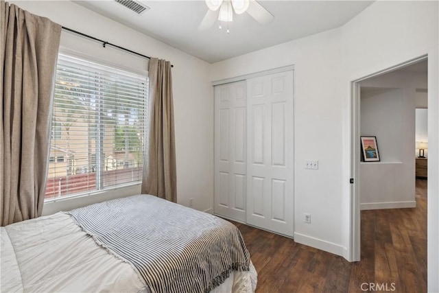 bedroom with baseboards, visible vents, wood finished floors, a closet, and ceiling fan