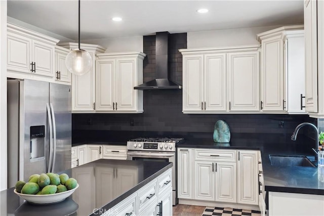 kitchen with dark countertops, a sink, decorative backsplash, stainless steel appliances, and wall chimney exhaust hood