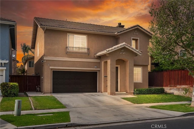 mediterranean / spanish home featuring fence, a tiled roof, stucco siding, concrete driveway, and a garage