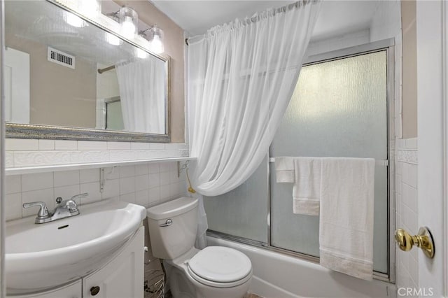 bathroom featuring combined bath / shower with glass door, vanity, tile walls, toilet, and visible vents