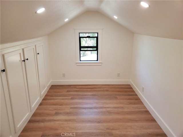 additional living space with lofted ceiling, baseboards, recessed lighting, and light wood finished floors