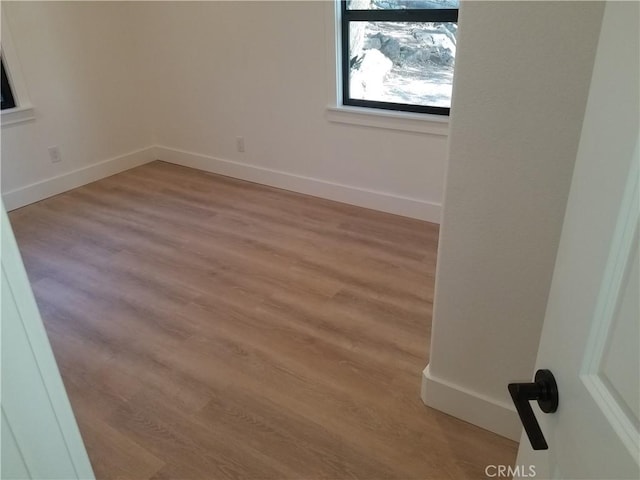 empty room with light wood finished floors and baseboards