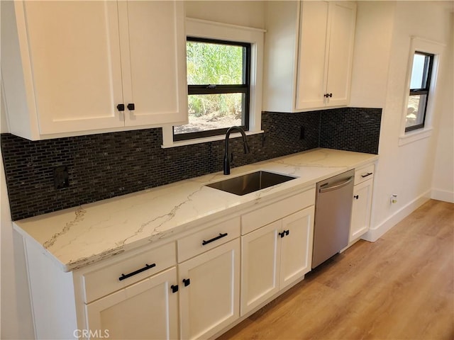 kitchen featuring a sink, light wood-style floors, white cabinetry, light stone counters, and dishwasher