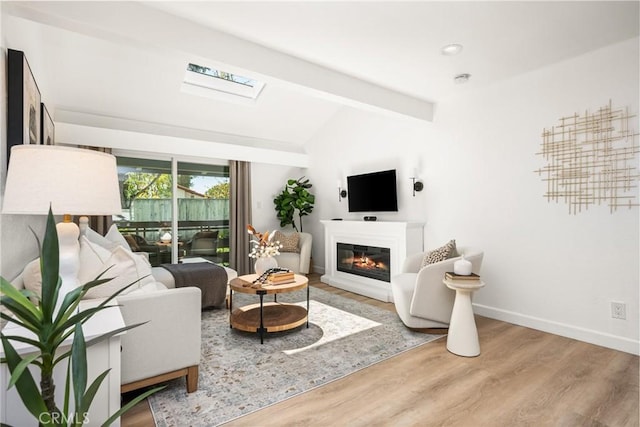 23732 Hillhurst Dr Unit 32, Laguna Niguel, CA 92677 - living room featuring vaulted ceiling with skylight, wood finished floors, a glass covered fireplace, baseboards, and recessed lighting