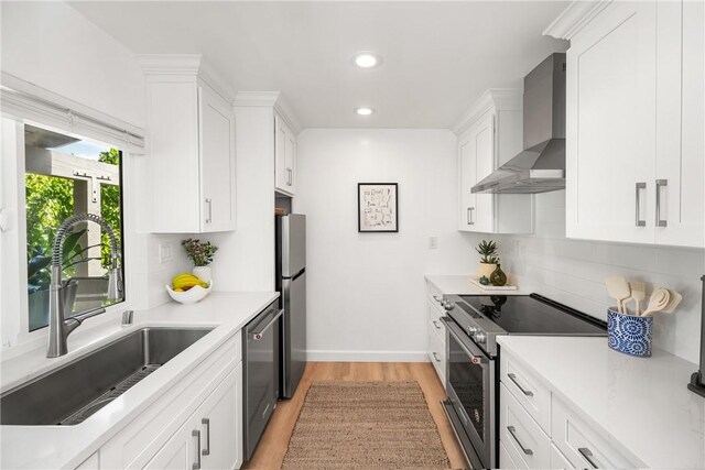 23732 Hillhurst Dr Unit 32, Laguna Niguel, CA 92677 - kitchen with a sink, stainless steel appliances, light wood-style flooring, wall chimney exhaust hood, and white cabinetry