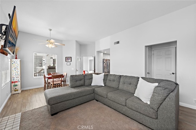living room with wood finished floors, visible vents, ceiling fan, and baseboards
