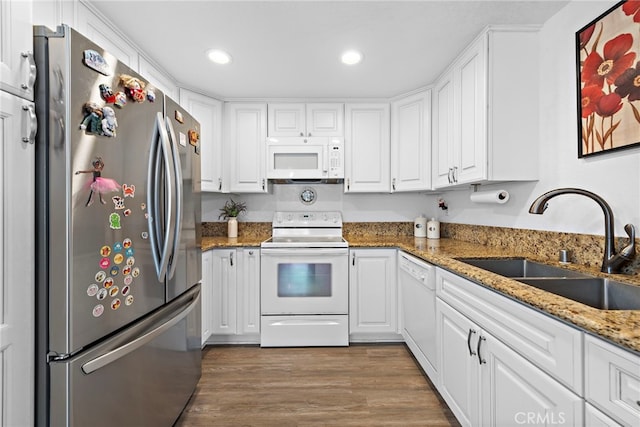 kitchen with dark wood finished floors, a sink, white cabinetry, and white appliances