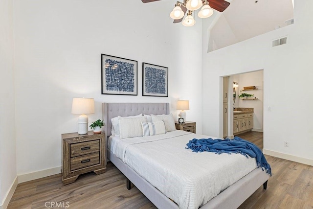 20371 Bluffside Cir Unit B401, Huntington Beach, CA 92646 - bedroom with high vaulted ceiling, wood finished floors, ensuite bath, baseboards, and visible vents