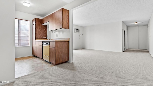 kitchen featuring brown cabinetry, light countertops, a wall mounted AC, baseboards, and dishwashing machine