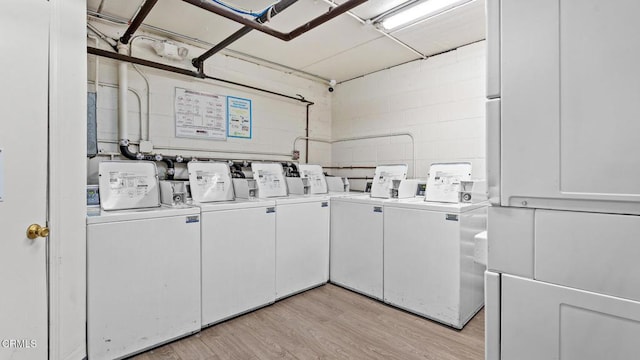 shared laundry area featuring light wood-type flooring, separate washer and dryer, and concrete block wall