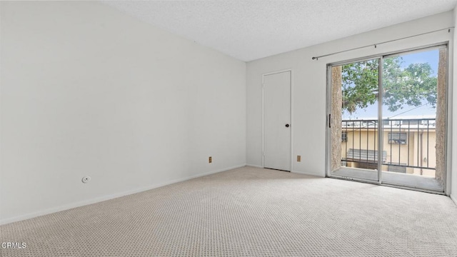 empty room featuring a textured ceiling, light colored carpet, and baseboards