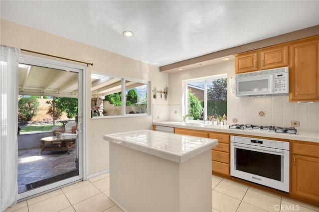 17381 Yorkshire Ave, Yorba Linda, CA 92886 - kitchen featuring a healthy amount of sunlight, light tile patterned floors, white appliances, and tile counters
