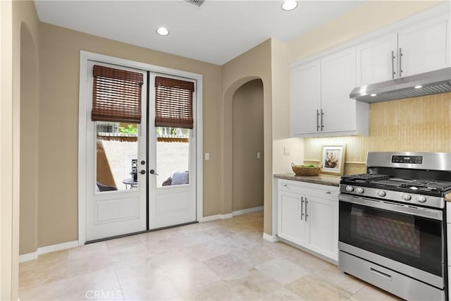 kitchen featuring baseboards, stainless steel gas range oven, arched walkways, and under cabinet range hood