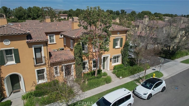 view of front of property with a chimney, stucco siding, a tiled roof, and a residential view